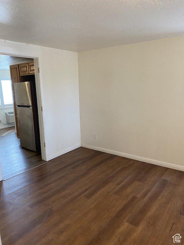 570 W Main St, Green River, UT 84525 - empty room featuring baseboards, a textured ceiling, dark wood finished floors, and a wall unit AC