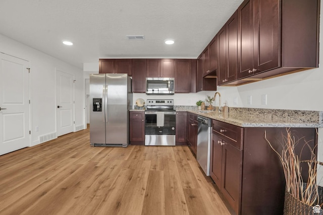 kitchen with a sink, stainless steel appliances, light wood-style floors, and visible vents