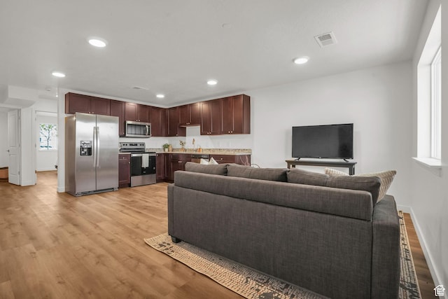 living room with light wood finished floors, visible vents, recessed lighting, and baseboards