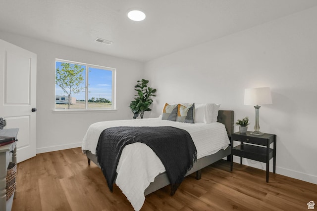 bedroom with wood finished floors, visible vents, and baseboards