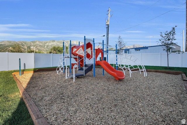 community play area with a mountain view and a fenced backyard