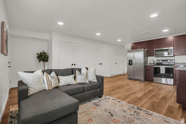 living room with recessed lighting, light wood-type flooring, and baseboards