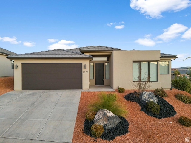 prairie-style home with a garage, driveway, and stucco siding
