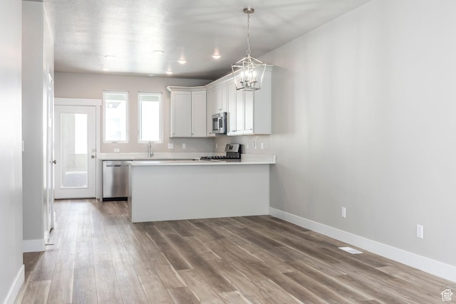 1082 S 2810 E, Spanish Fork, UT 84660 - kitchen with a peninsula, wood finished floors, a sink, stainless steel appliances, and a notable chandelier