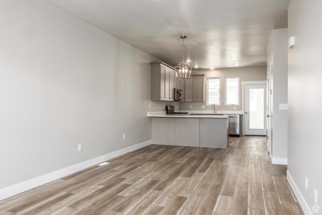 1082 S 2810 E, Spanish Fork, UT 84660 - kitchen featuring a chandelier, a peninsula, light countertops, stainless steel appliances, and light wood finished floors
