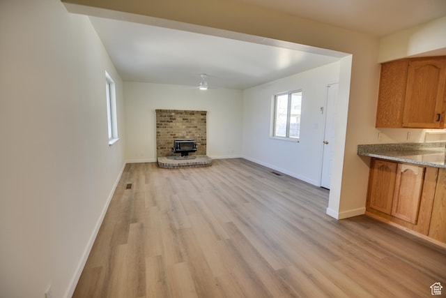 265 E Center St, Beaver, UT 84713 - unfurnished living room featuring a fireplace, visible vents, baseboards, a ceiling fan, and light wood-style floors