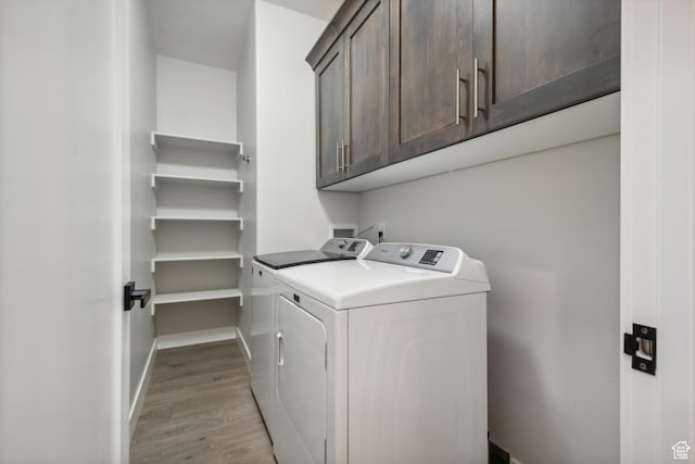 laundry area featuring baseboards, cabinet space, light wood-style flooring, and independent washer and dryer