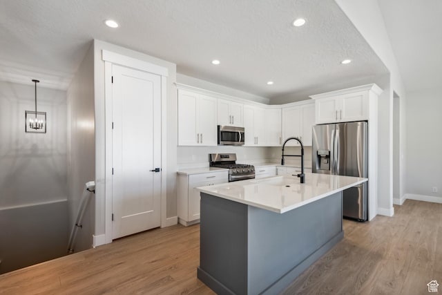 kitchen with white cabinets, light wood-style flooring, a sink, and appliances with stainless steel finishes
