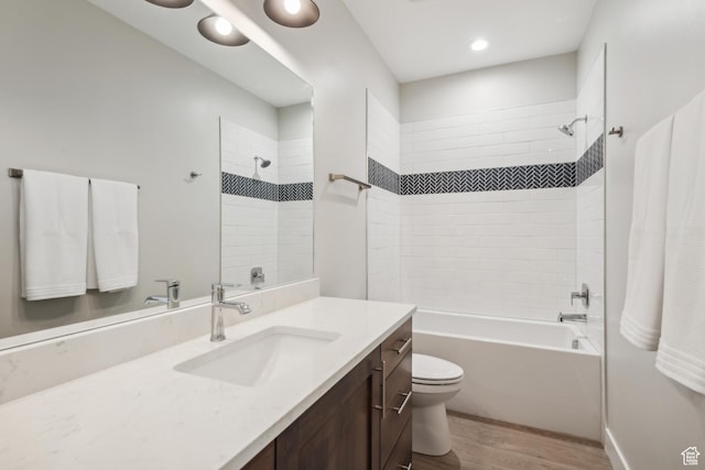 bathroom with toilet, wood finished floors, vanity, and shower / bath combination