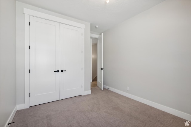 unfurnished bedroom with carpet floors, baseboards, and a closet