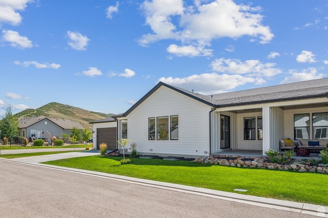 ranch-style house with driveway, a front yard, an attached garage, a porch, and a mountain view