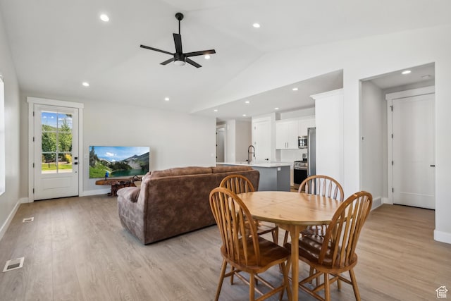 dining space featuring visible vents, lofted ceiling, light wood-type flooring, and a ceiling fan