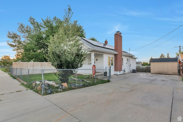 22 W 200 S, Tooele, UT 84074 - view of front of house featuring a shed, roof mounted solar panels, a chimney, an outdoor structure, and a fenced front yard