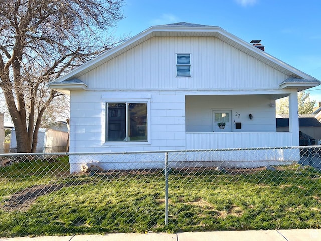 view of front of home with a porch, a chimney, a front lawn, and a fenced front yard