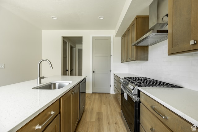 kitchen with wall chimney exhaust hood, light hardwood / wood-style flooring, backsplash, appliances with stainless steel finishes, and sink