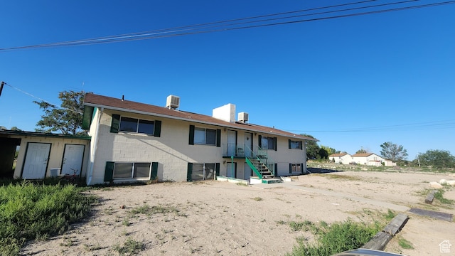 rear view of house with stairway, central AC unit, and brick siding