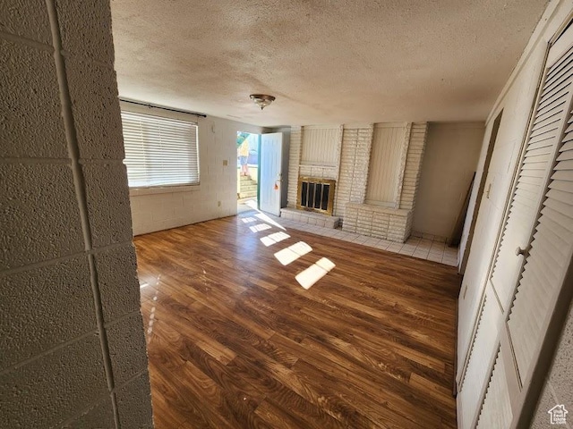 370 W 620 N, Castle Dale, UT 84513 - unfurnished living room featuring a brick fireplace, concrete block wall, wood finished floors, and a textured ceiling