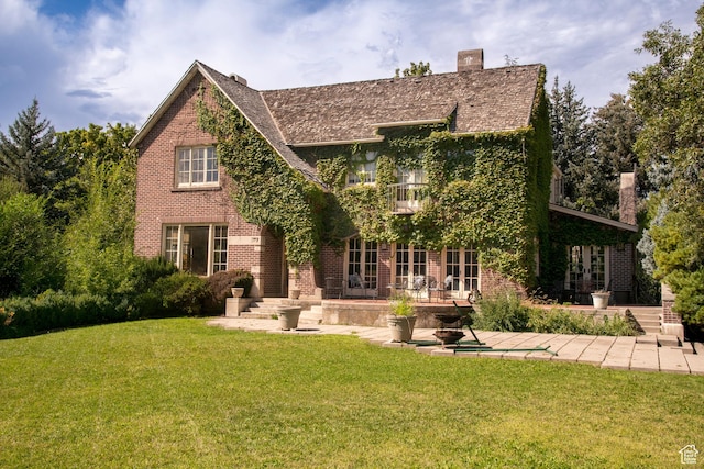 2633 E 6200 S, Holladay, UT 84121 - tudor house featuring a patio area, a balcony, brick siding, a front lawn, and a chimney