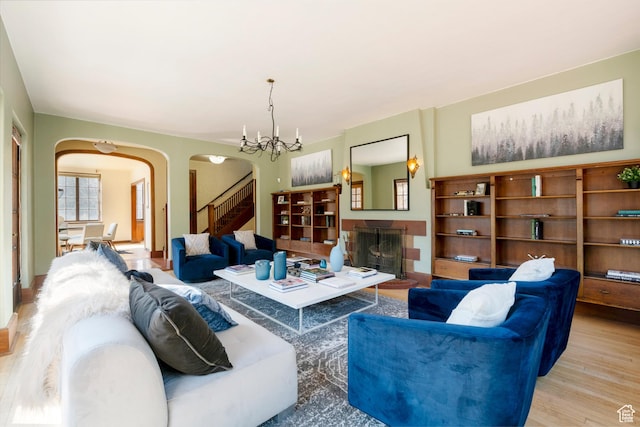 2633 E 6200 S, Holladay, UT 84121 - living area featuring arched walkways, wood finished floors, stairway, a fireplace with raised hearth, and a chandelier