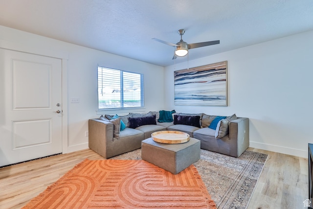 living area featuring baseboards, ceiling fan, and wood finished floors
