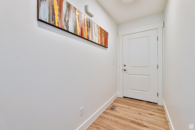 doorway featuring light wood-type flooring, baseboards, and visible vents