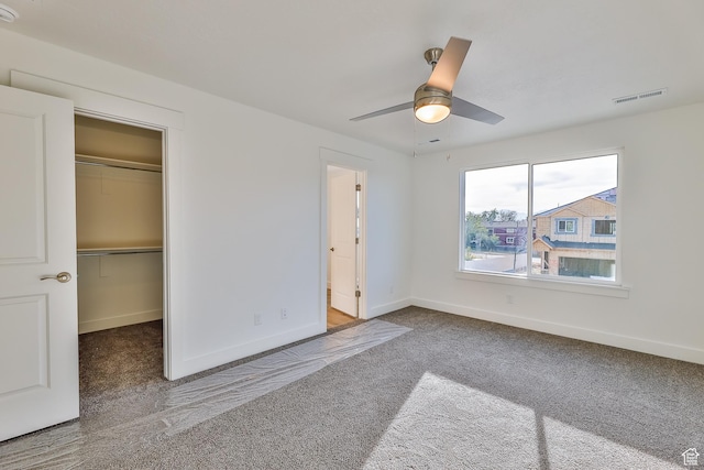unfurnished bedroom featuring a walk in closet, visible vents, baseboards, a closet, and carpet flooring