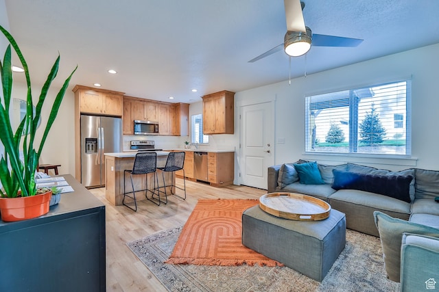 living area with recessed lighting, a ceiling fan, and light wood finished floors