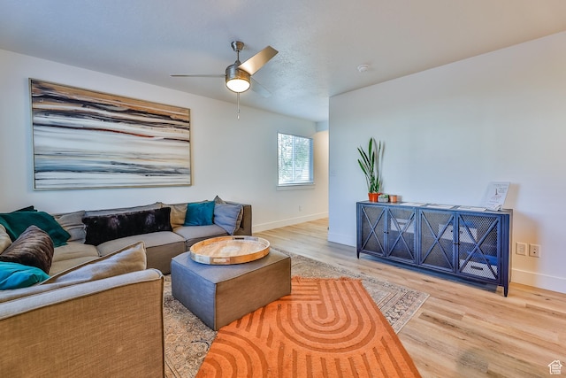 living room featuring baseboards, a ceiling fan, and wood finished floors