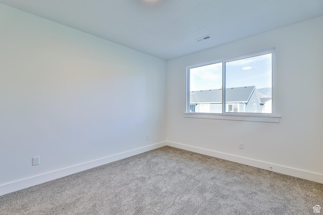 carpeted empty room featuring baseboards and visible vents