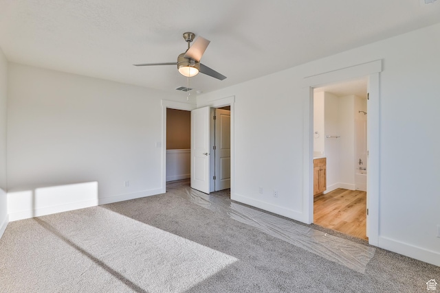 unfurnished bedroom with connected bathroom, light colored carpet, a ceiling fan, baseboards, and visible vents