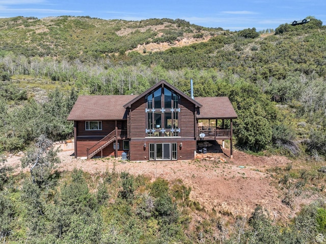 back of property with log veneer siding, a deck with mountain view, stairway, and roof with shingles
