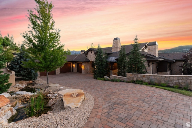 340 Hollyhock St, Park City, UT 84098 - view of front of home with curved driveway, an attached garage, a chimney, and stone siding