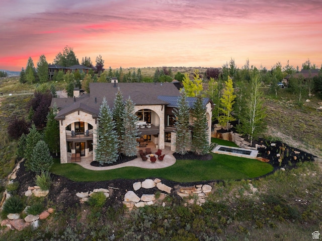 340 Hollyhock St, Park City, UT 84098 - back of house at dusk with a balcony, a patio area, a chimney, and a yard