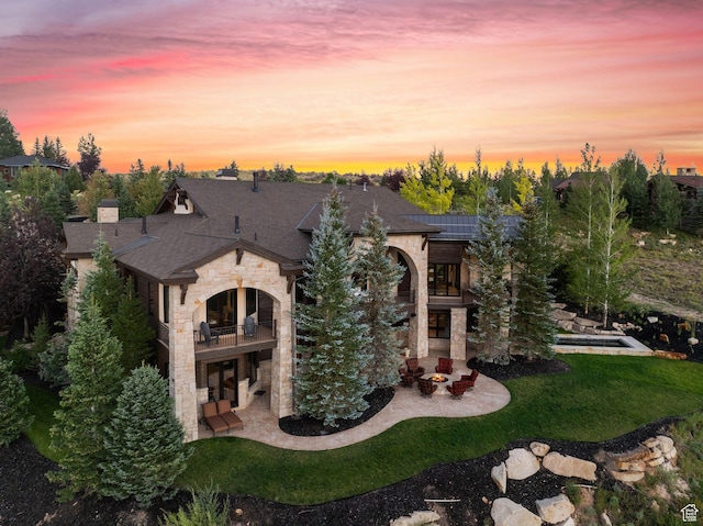340 Hollyhock St, Park City, UT 84098 - back of property at dusk featuring stone siding, a patio area, a yard, and a balcony