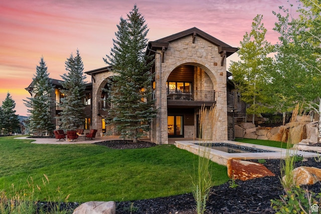 340 Hollyhock St, Park City, UT 84098 - back of property at dusk with a lawn, stone siding, a patio, and french doors