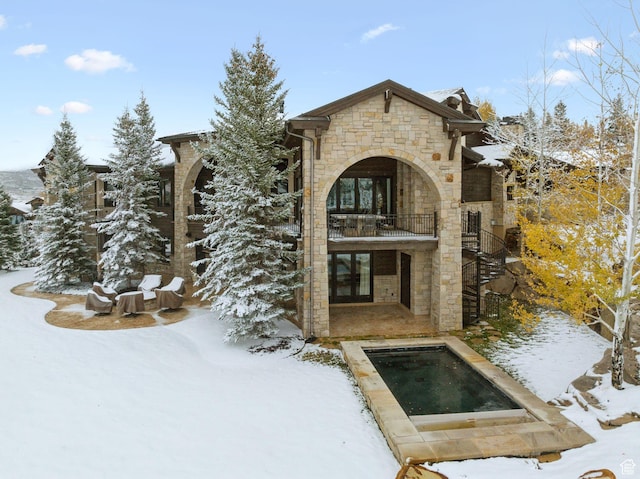 340 Hollyhock St, Park City, UT 84098 - snow covered rear of property with a hot tub, stairway, stone siding, and a balcony