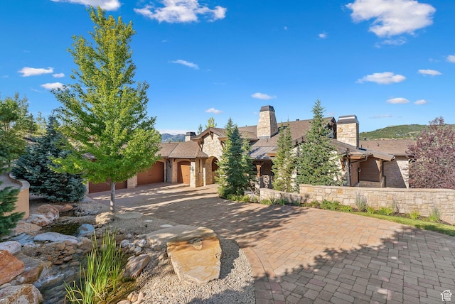 340 Hollyhock St, Park City, UT 84098 - view of front of house with stone siding, driveway, a chimney, and an attached garage