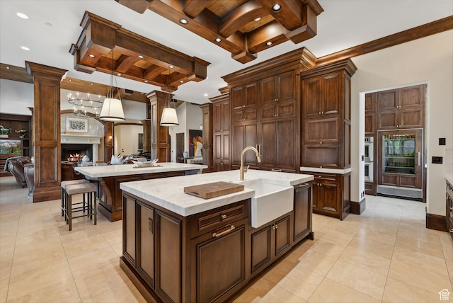 340 Hollyhock St, Park City, UT 84098 - kitchen featuring an island with sink, a sink, a fireplace, open floor plan, and light countertops