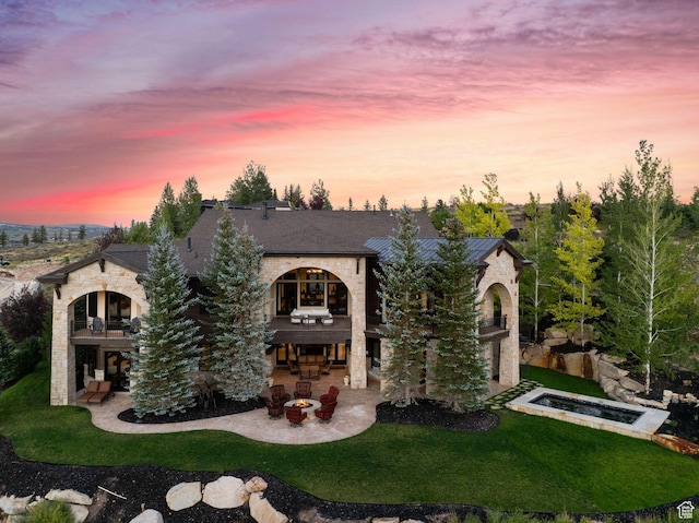 340 Hollyhock St, Park City, UT 84098 - view of front facade featuring a patio area, a fire pit, stone siding, a balcony, and a lawn