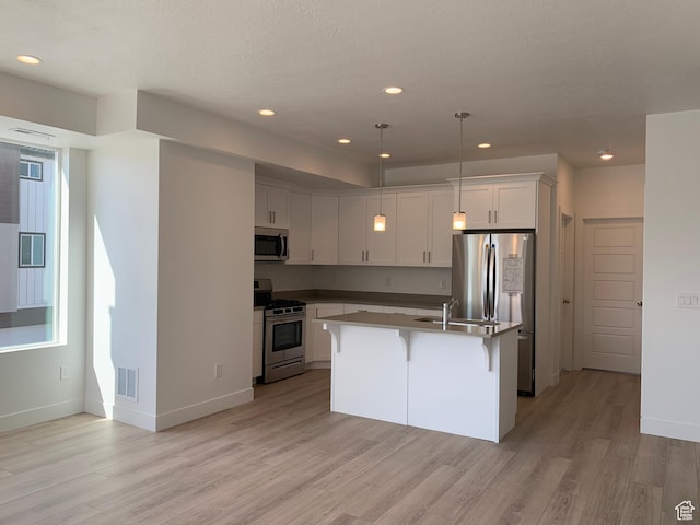 kitchen featuring light wood-style flooring, a kitchen island with sink, appliances with stainless steel finishes, and visible vents