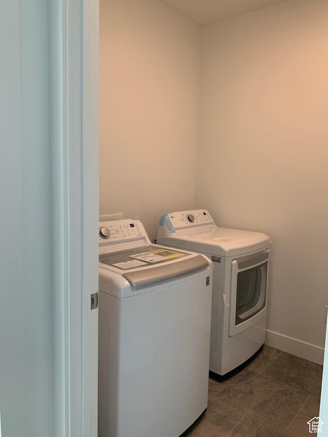 clothes washing area with independent washer and dryer, dark tile patterned floors, baseboards, and laundry area