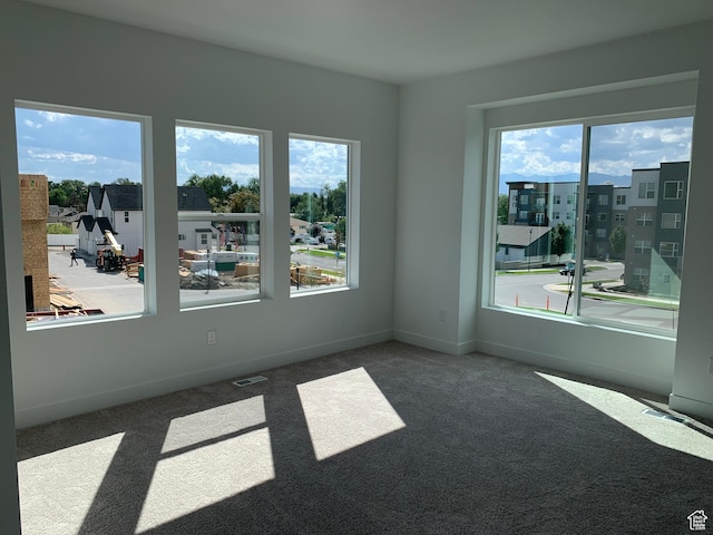 spare room featuring carpet flooring, baseboards, and visible vents