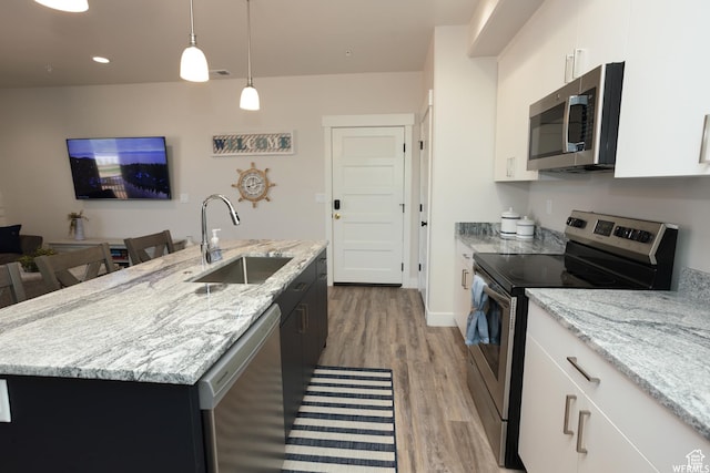 553 S 100 W Unit 203, Richfield, UT 84701 - kitchen with stainless steel appliances, light wood finished floors, a kitchen island with sink, hanging light fixtures, and light stone counters