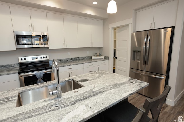 553 S 100 W Unit 203, Richfield, UT 84701 - kitchen with stainless steel appliances, wood finished floors, a breakfast bar area, recessed lighting, and light stone counters
