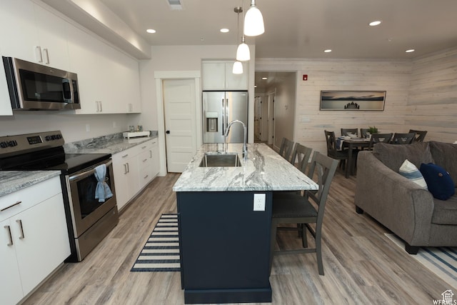 553 S 100 W Unit 203, Richfield, UT 84701 - kitchen featuring stainless steel appliances, a kitchen breakfast bar, open floor plan, white cabinets, and light wood finished floors