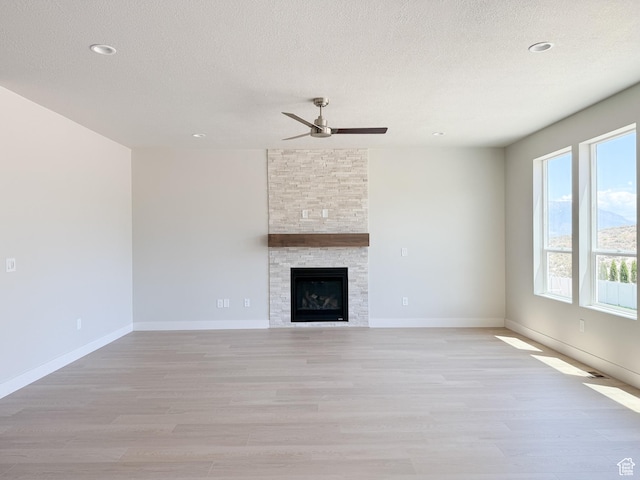 1546 S Lukas Ln, Saratoga Springs, UT 84045 - unfurnished living room with a ceiling fan, light wood-style flooring, a textured ceiling, a fireplace, and recessed lighting