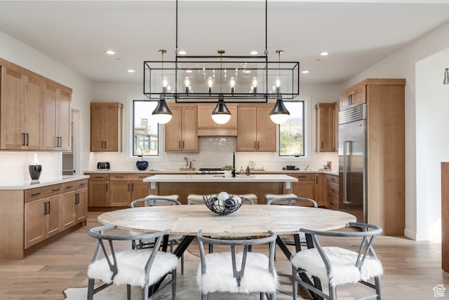 kitchen featuring stainless steel built in fridge, light wood-type flooring, light countertops, and a center island