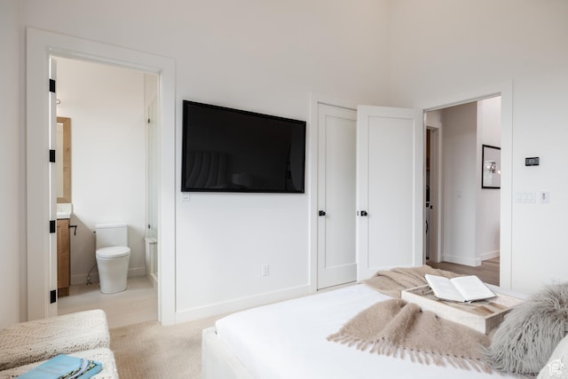 bedroom with light carpet, baseboards, a closet, and connected bathroom