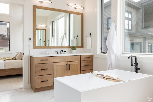 full bathroom with marble finish floor, a freestanding tub, and vanity
