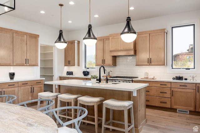 kitchen with an island with sink, light countertops, a kitchen bar, and light wood-type flooring